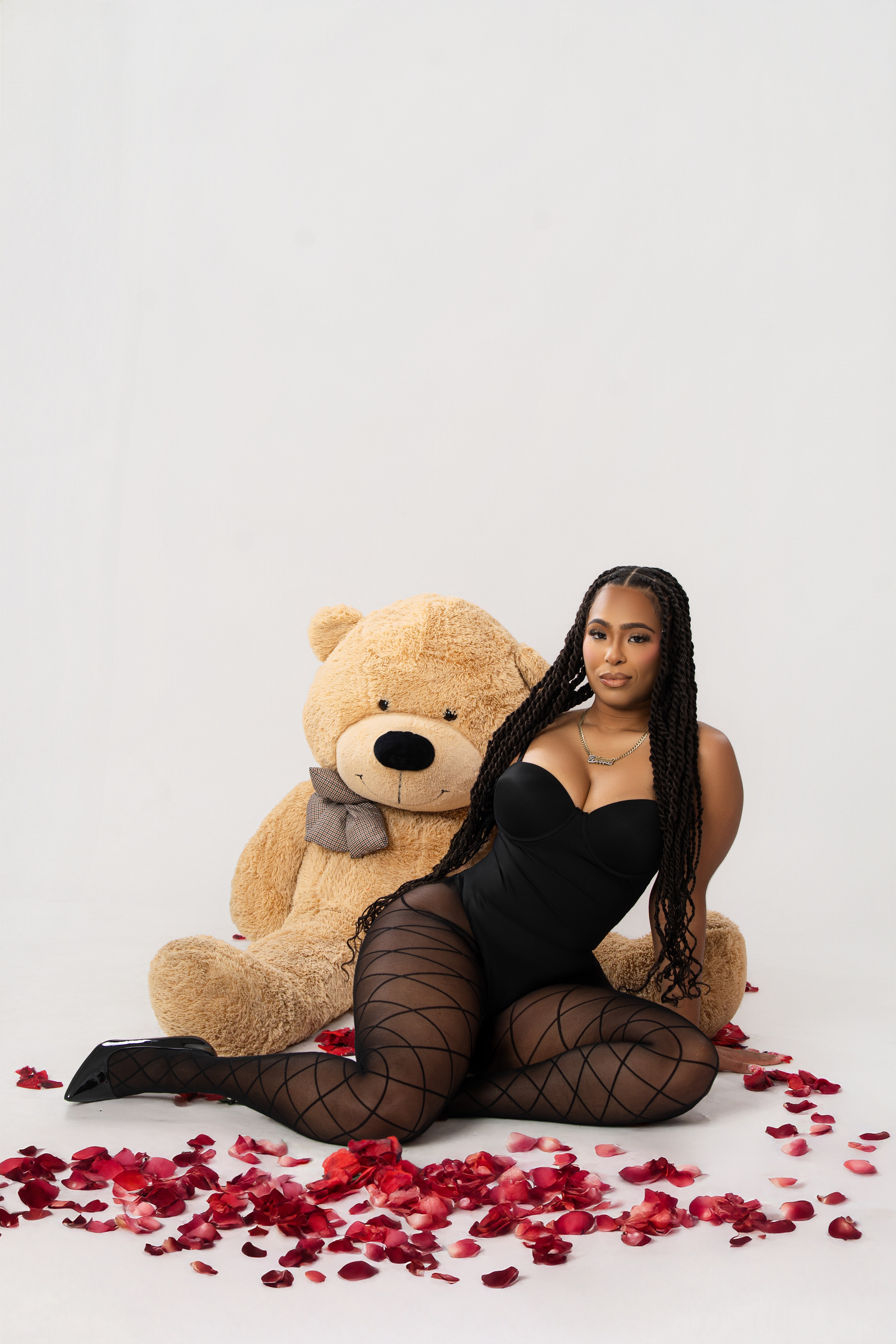 Woman posing with a teddy bear and rose petals during a creative self portrait session
